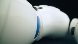 CU, 매크로 보기, 이동 캠:밝은 파란색 장식 요소가 있는 재미있는 흰색 플라스틱 깨진 장난감 로봇은 어두운 방에 극단적으로 가까운... 