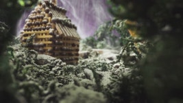 CU, 매크로 보기: 눈이 올 때 숲 속의 연기에 있는 스텁 근처에 성냥으로 만든 작은 건물 모델이 있는 소형 무대 장면 최대 확대 알파 채널... 