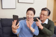  스마트폰을 사용하여 집에서 영상 통화를 하는 노인