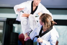 People in a gym in martial arts training exercising Taekwondo, both have a black belt | Stock Photo | Colourbox