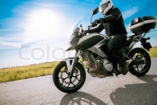 Biker in helmet riding a road motorbike on a sunny day. | Stock Photo | Colourbox