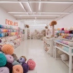 도라스담바얀(DORA`S TAMBAYAN) | A yarn shop with lots of yarn, pastel colored in a white room with a strip light written "Dora's yarn" - AI 이미지 생성기 프롬프트