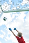 Back view portrait of teenage boy jumping and catching ball while defending gate in football match | 유토이미지 | 상세페이지...