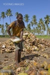 Worker dehusking coconuts (Cocos nucifera) for the further processing to copra, Quelimane, Mozambique, Africa - 당신의 크리에이티브...